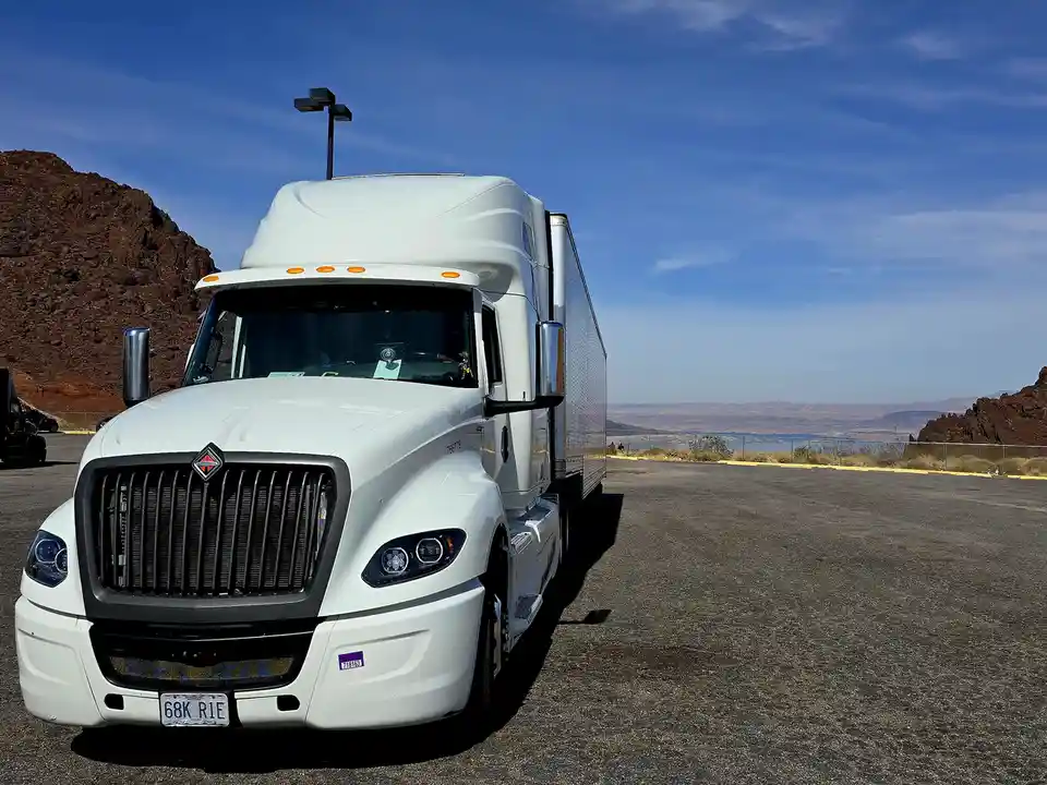 A white International semi-truck with a Missouri license plate reading '68K R1E' is parked in a desert overlook parking lot…
