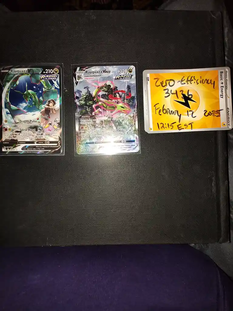 Three Pokémon trading cards are laid out on a dark textured surface. The left card is a basic Rayquaza with 210 HP. The…