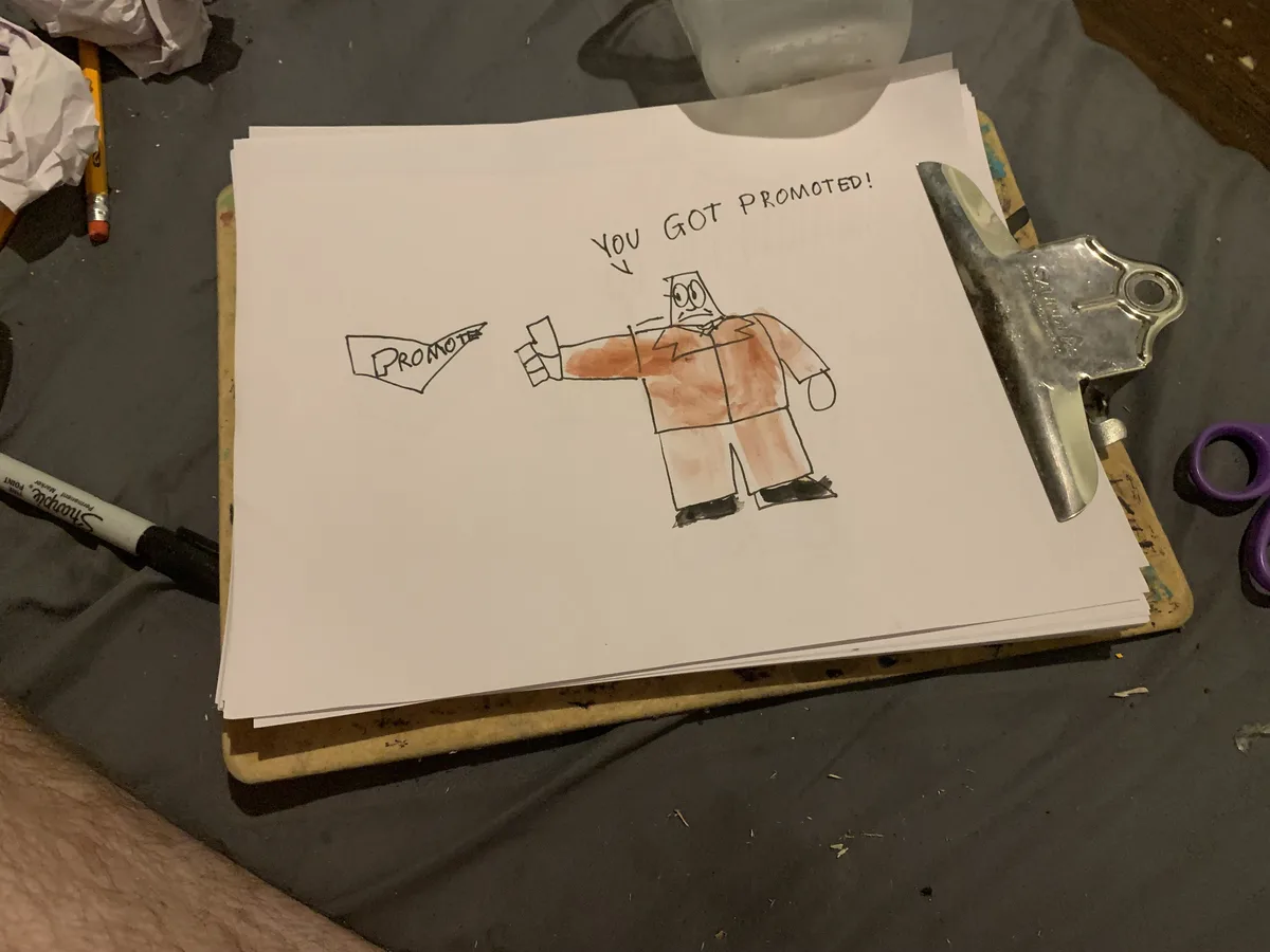 A hand-drawn cartoon on paper shows a stick figure in an orange suit holding a sign that says 'PROMOTE'. Above the figure…