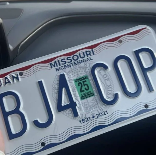 A close-up photo of a Missouri state license plate with the registration number 'BJ4 COP' visible. The plate commemorates…