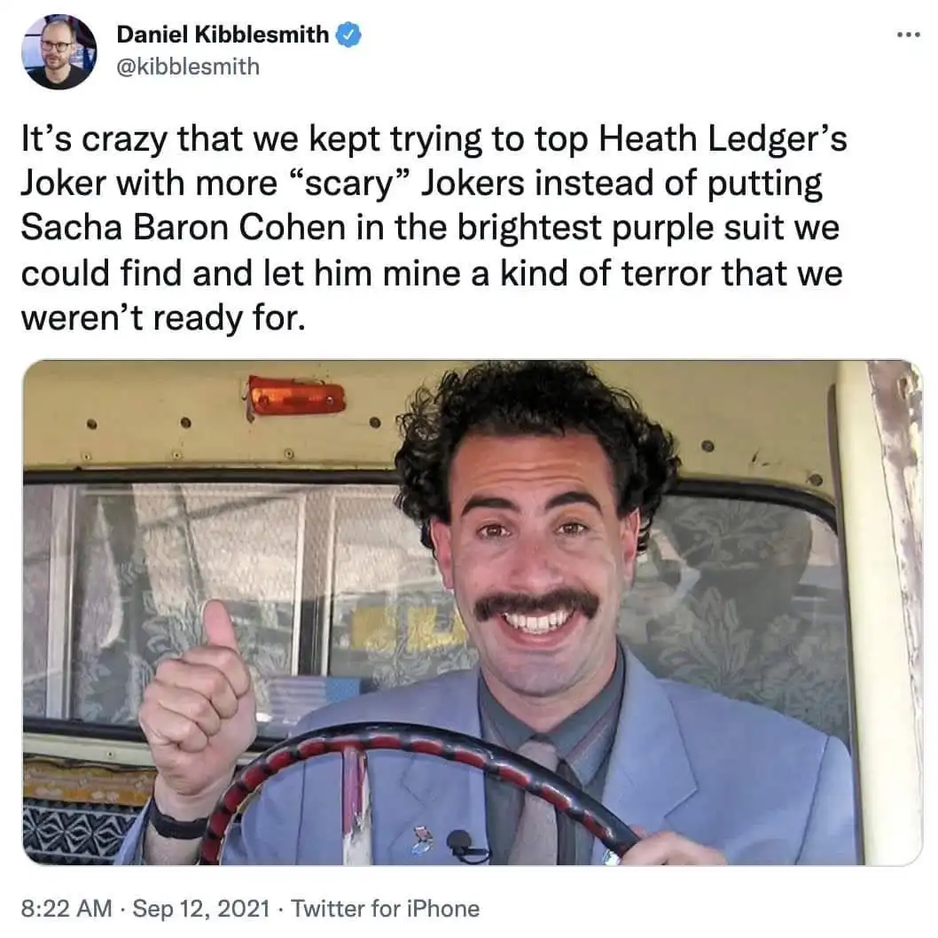 A screenshot of a tweet by Daniel Kibblesmith showing a photo of actor Sacha Baron Cohen smiling broadly while driving a…