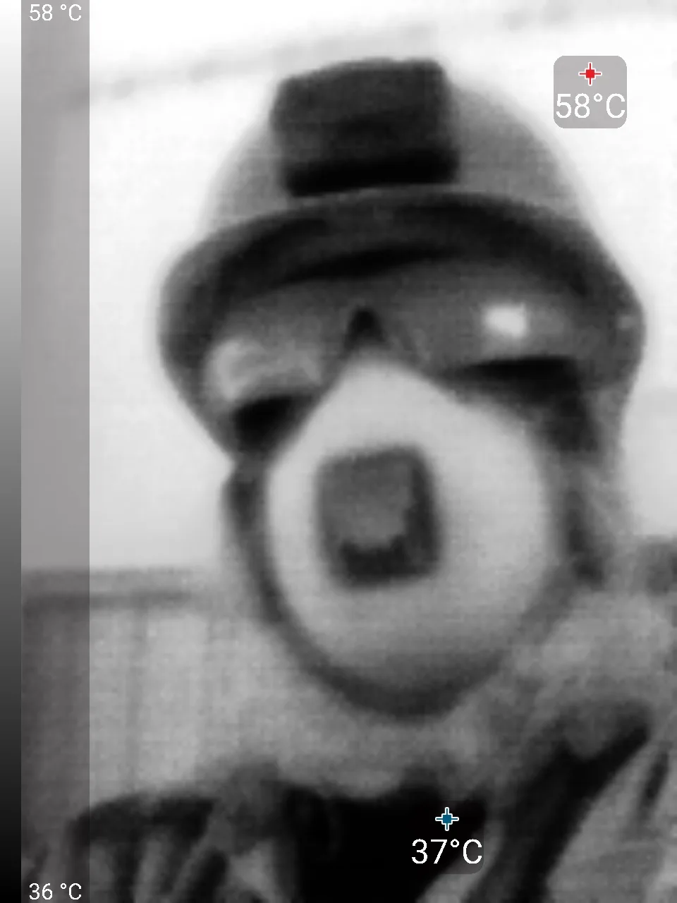 A blurry thermal imaging photo shows a person wearing a helmet and face mask, with temperature readings overlaid: 58°C on…