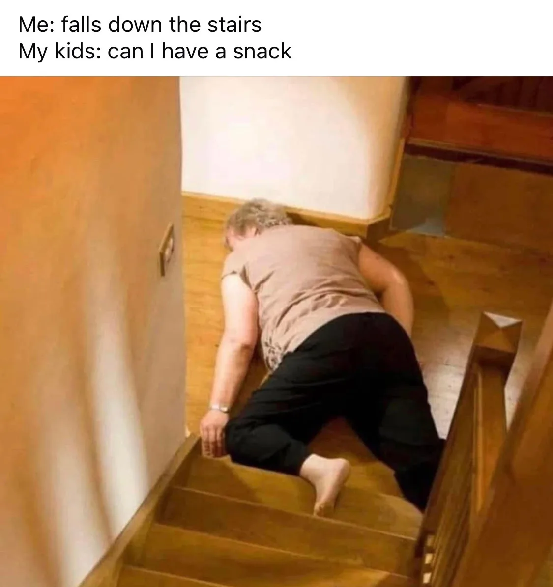 A person is lying face down on wooden stairs, appearing injured or dazed after a fall. The overlaid text reads 'Me: falls…