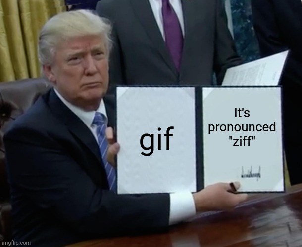 A man in a suit sits at a desk holding two whiteboards. The left board says 'gif' and the right board says 'It's pronounced…