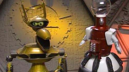 Two robots stand side by side; the gold one on the left has a surprised expression with wide eyes and an open mouth, while…