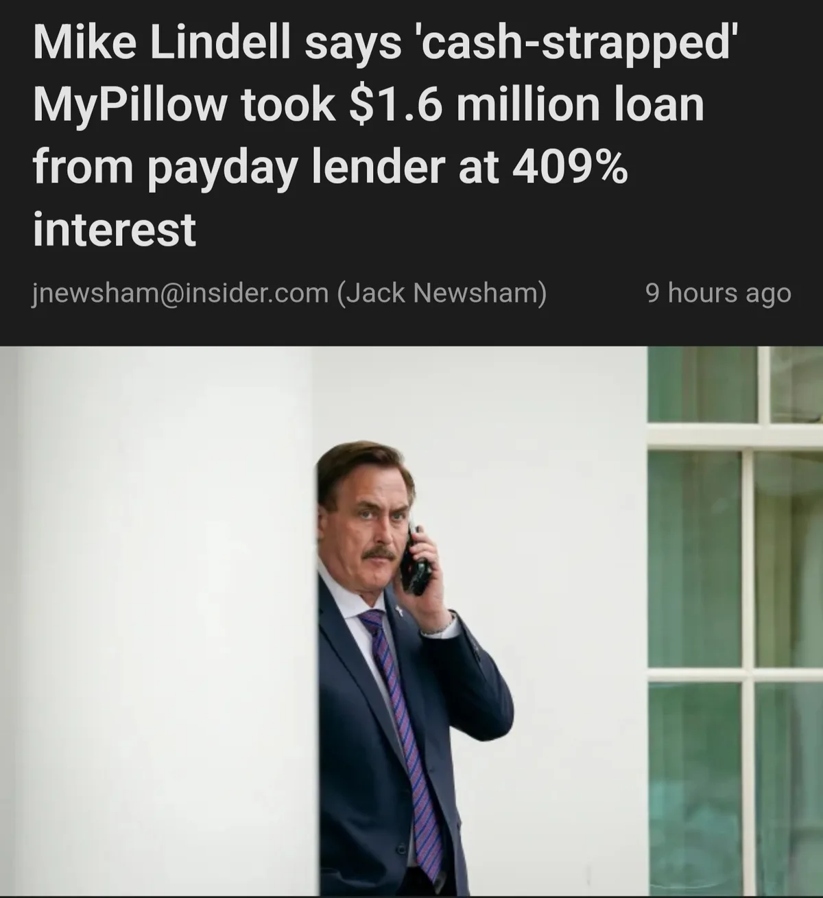A man in a suit and tie peeks around a white pillar while holding an old-style cell phone to his ear, with a news headline…